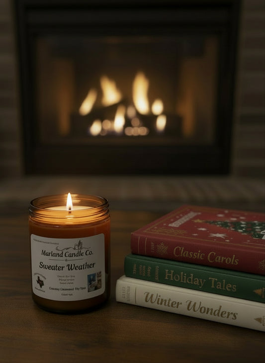 Jar of candle labeled 'Sweeter Weather' on a wooden surface with blurred background